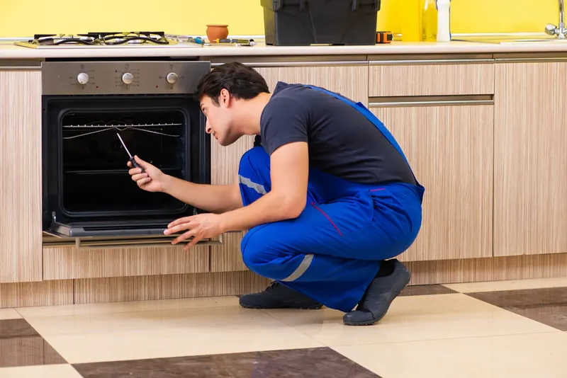 Monteur prüft einen eingebauten Backofen
